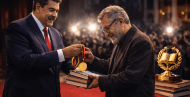 Nicolás Maduro entrega un trofeo en una ceremonia literaria; mesa con libros en primer plano y luces de teatro al fondo.