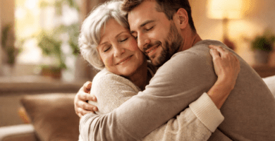 Hijo adulto abrazando con ternura a su madre mayor en casa para expresar amor y gratitud en vida