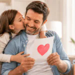 Papá sonríe mientras recibe una tarjeta del Día del Padre con un corazón dibujado y un beso de su hija