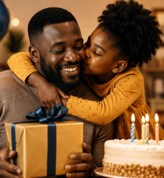 Padre afrodescendiente celebrando su cumpleaños mientras recibe un beso y un regalo de su hija