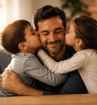 Padre sonriente recibe besos de sus hijos en un hogar cálido, escena familiar para poemas del Día del Padre.