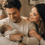 Esposo primerizo sosteniendo a su bebé junto a su esposa en un momento tierno del Día del Padre