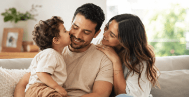 Novio que es papá sonriendo con su hijo mientras su pareja lo acompaña con ternura en casa.