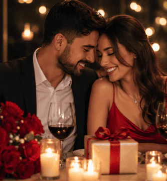 Pareja celebrando su aniversario de bodas en una cena romántica con velas, rosas rojas, regalo y luces cálidas.