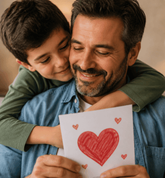Hijo abrazando a su papá mientras le entrega una tarjeta hecha a mano como muestra de amor y agradecimiento.