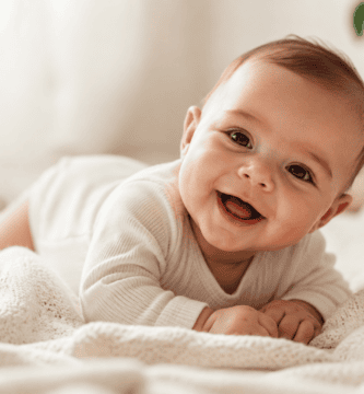 Bebé sonriente sobre una manta clara en una fotografía tierna y luminosa