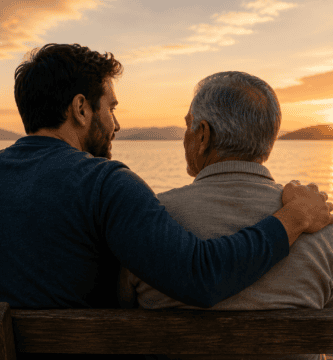 Padre mayor y su hijo adulto sentados junto a un lago al atarde